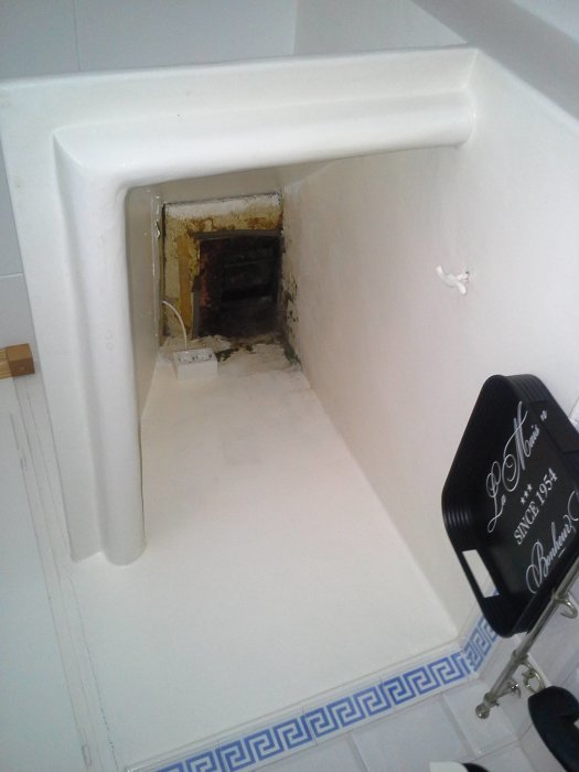 Öppning för spiskåpa med synligt ventilationshål och delvis kaklad vägg i ett kök.