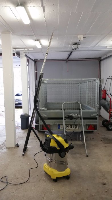 En dammsugare kopplad till en förlängningsstång för att minska damm vid borrning i ett garage.