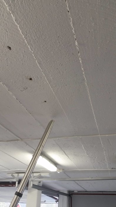 Tak med borrade hål och pluggar, klar för kabeldragning i ett garage.