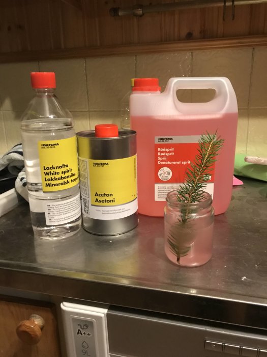 Flaskor och burkar med lacknafta, aceton och t-röd på ett köksbord, hemgjort recept för limborttagning.