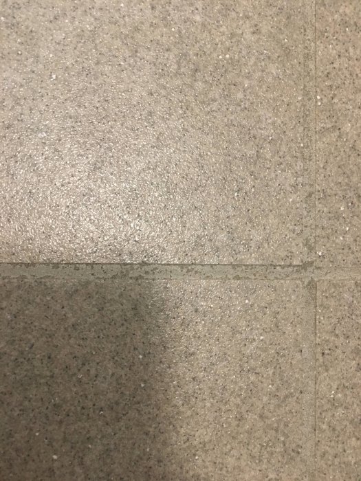 Fläckiga och ojämna fogar på ett sex månader gammalt badrumsgolv.