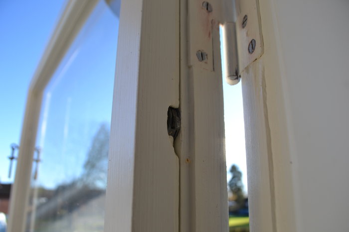 Koppelkrok för fönster monterad synlig på fönsterkarmen, slitage syns där den brukar vara dold.