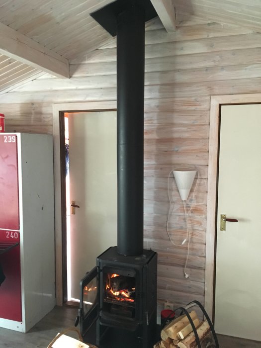 Brinnande ved i en öppen kamin med svart skorsten inomhus, fråga om dess effektivitet.