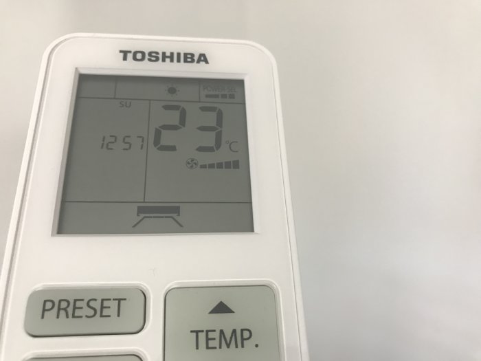 Närbild av en Toshiba AC-kontrollenhet som visar 23 grader Celsius på displayen.