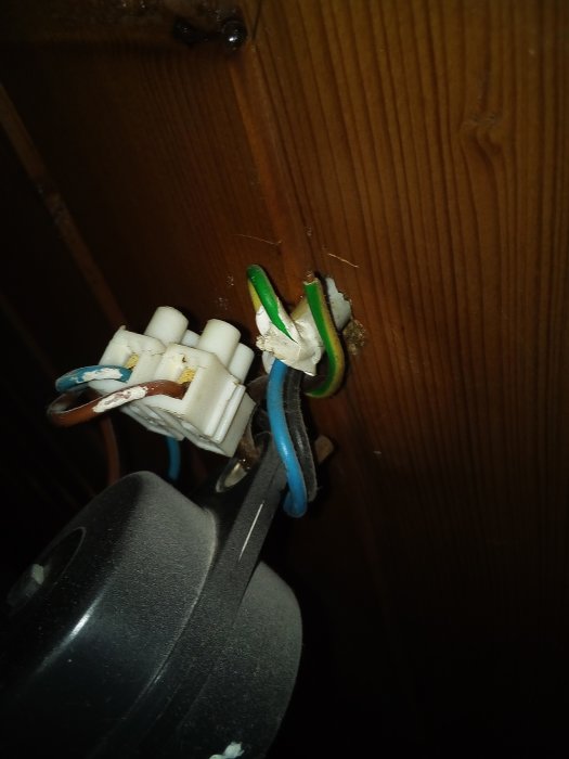Öppnad takdosa med synliga ledningar och anslutningar för en höj- och sänkbar lampa mot ett träpaneltak.