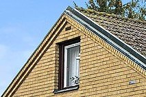 Husnock med ovanlig tegelfasad och kopparplåt som vindskivor runt fönstret.