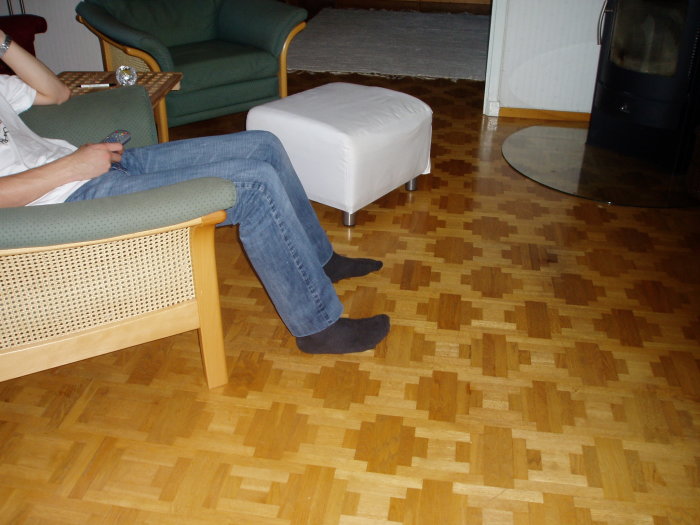 Inredningsbild med stramt parkettgolv i kvadratiskt mönster från 60-talet, del av rum med möbler.