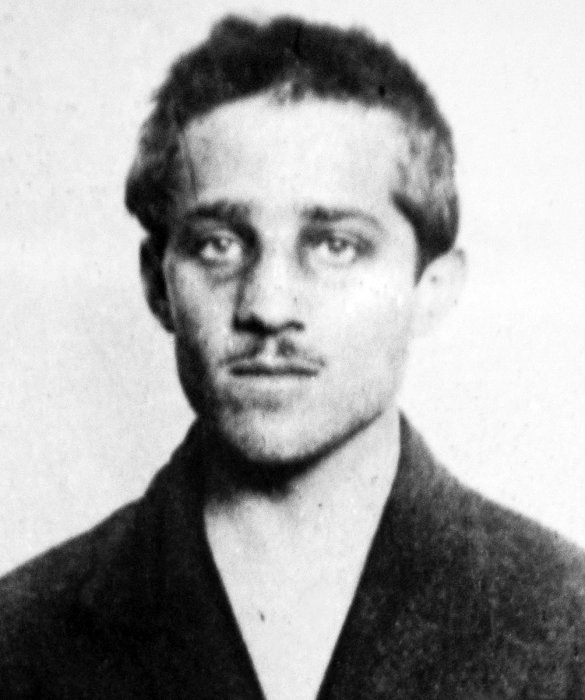 Svartvit bild på en ung man i mörk kavaj från tidigt 1900-tal, allvarlig uppsyn.