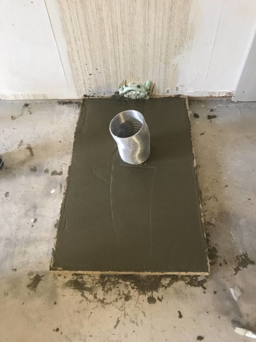 Nybyggd betongklack med tilluftsrör för kamin, i ett garage i väntan på installation.
