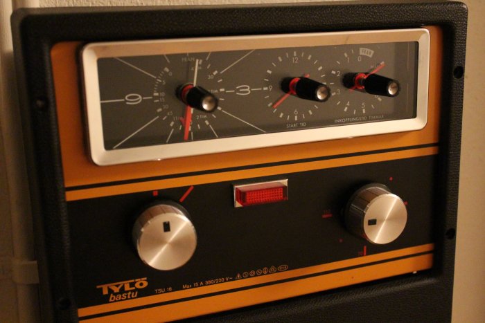 Äldre manöverpanel för bastu med två vred, reglage för timer och temperatur, märkt med "TYLÖ bastu".