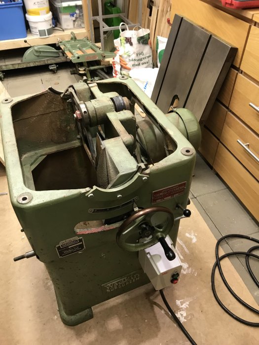 En Wadkin Bursgreen AGS 12 bordssåg i en snickarbod, avmonterad med sågbordet borttaget och exponerade inre komponenter.