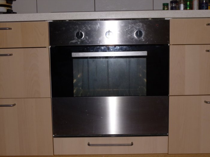 Egeninstallerad ugn och häll i kök med 6 mm springa mellan ugn och bänkskiva, omgiven av ljusa skåpluckor.