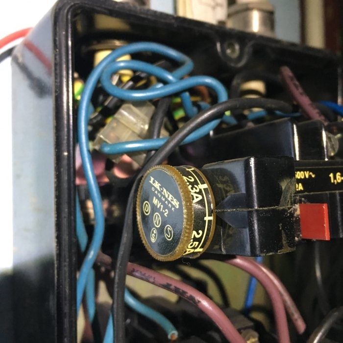 Interiör av elektrisk box med kablar och en synlig överbelastningsskyddsenhet.
