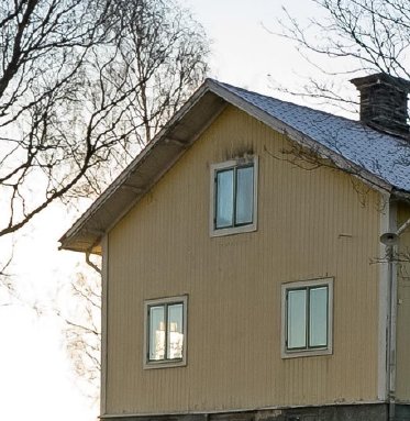 Gult hus med kondens på ett fönster som indikerar dålig ventilation på övervåningen.