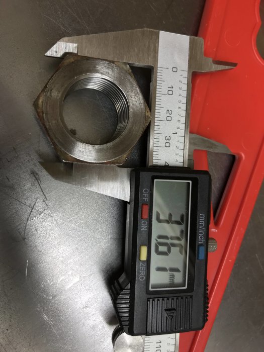 Sargad mutter mäts med skjutmått som visar 31,51 mm, redo för måttbestämning.