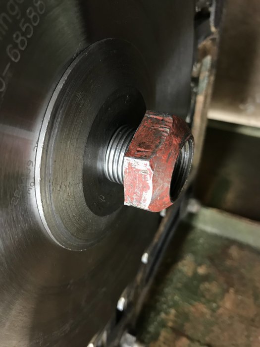 Sliten mutter på sågaxeln med synlig tråd nära en sågklinga, behov av dimensionering.