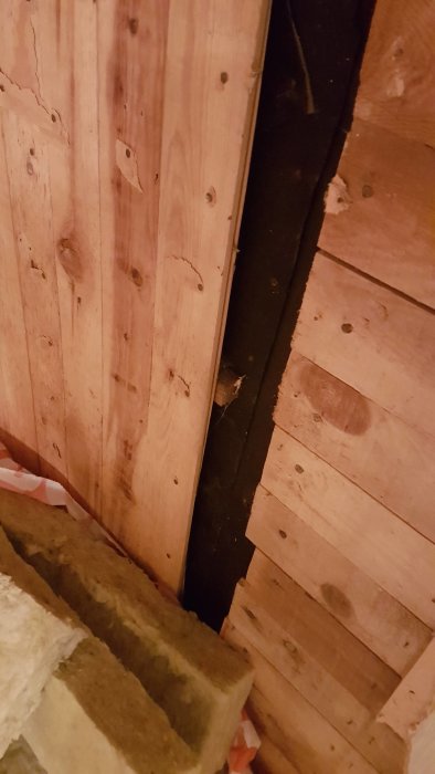 Vegg med trepanel og eksponert isolasjon i et hus under renovering.