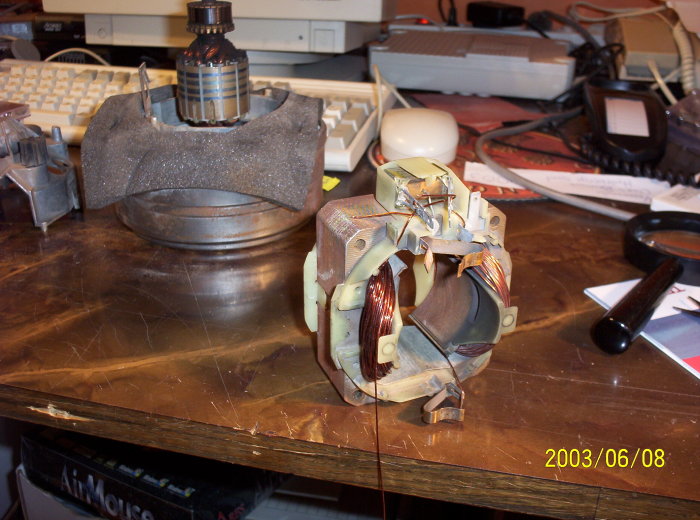 Elektrisk motor med synlig rotor och omvänd stator på ett arbetsbord med verktyg och elektronik.