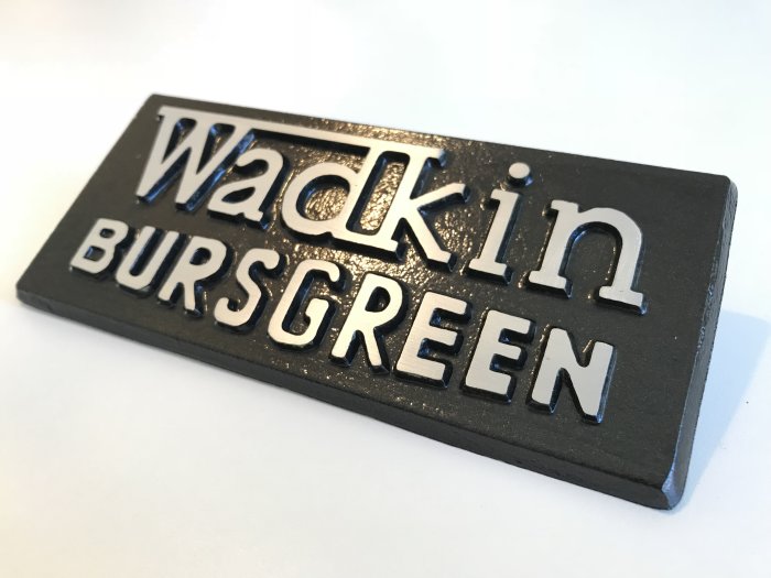 Färdigställd skylt med texten "Wadkin Bursgreen" i relief på en svart bakgrund.