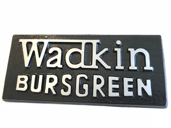 Svart skylt med upphöjda bokstäver som lyder "Wadkin Bursgreen" med en glansig finish.