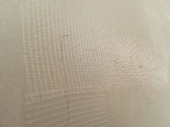 Glasfiberväv applicerad på en vägg för att reparera en spricka i bredspackling.