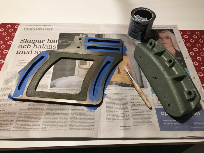 Renoveringsprojekt med verktygsfäste som är maskerat för målning, pensel och öppen färgburk på tidningar.
