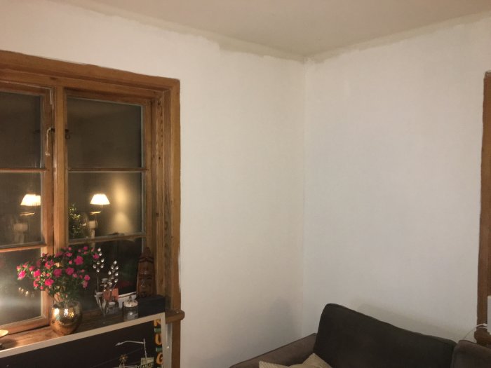 Ett hörn av ett rum med ett träfönster och väggar målade i ljus nyans nära Flugger 7S S0500-n.