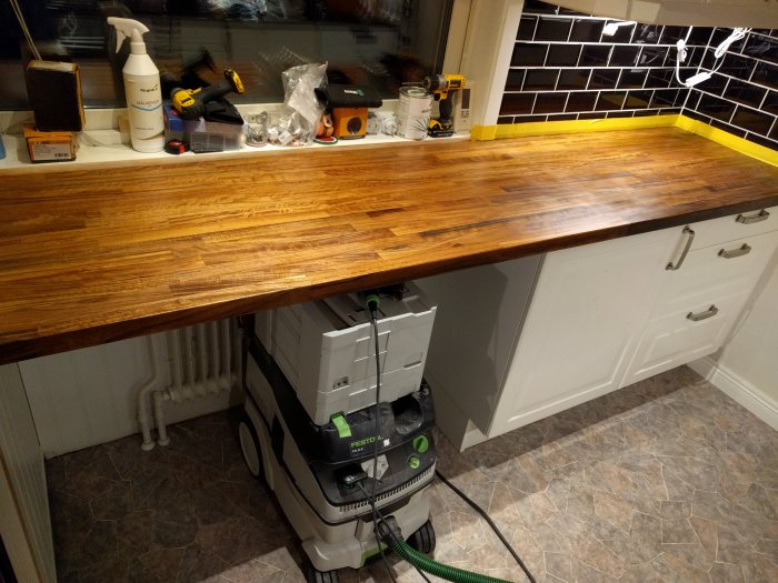 Nyinstallerad valnötsskiva på vit köksinredning med verktyg och byggmaterial på ytan.