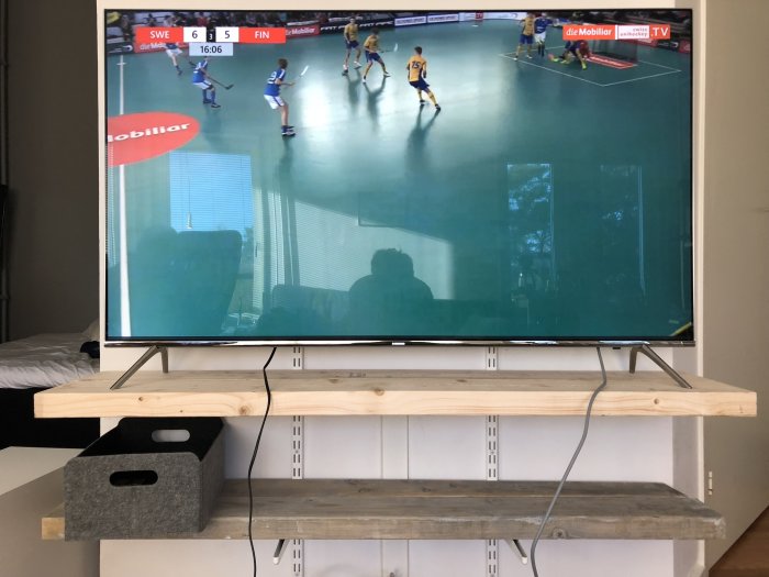 Tv med innebandymatch mellan Sverige och Finland, reflektion av person i rummet.