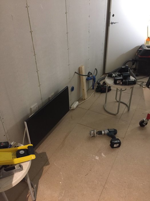 Renoveringsarbete med verktyg på golvet och nyinstallerat gips på vägg i byggprojekt.
