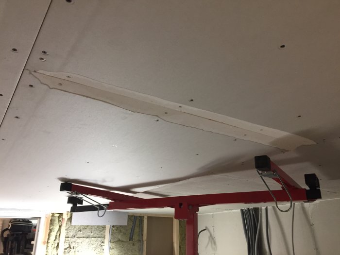 Nyinstallerade gipsplattor på tak med synlig skarv och ett lager spackel, samt takstöd.