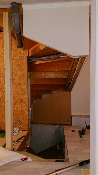 Ett oavslutat garagebygge med träramar, OSB-skivor och målarburkar.