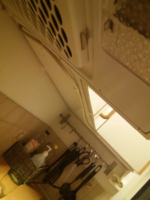 Köksinteriör med vinkelvy av bänkskåp, väggplattor och utanpåliggande eluttag bredvid ett fönster.