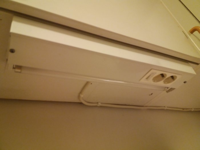 Eluttag under ett köksskåp med en urdragen skadad kabel och tomma kontaktplatser, utan anslutna apparater.