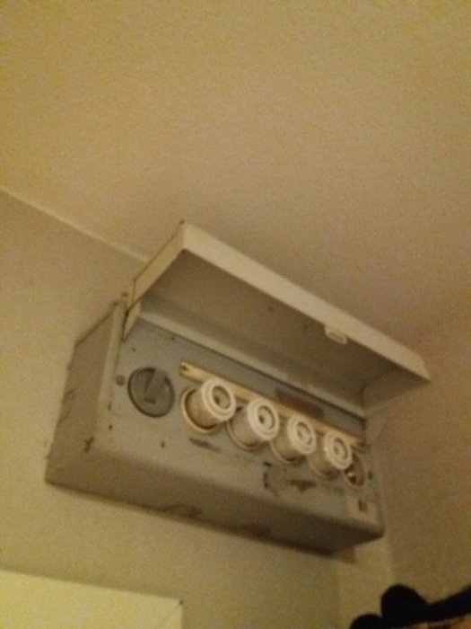 Öppen elcentral med synliga säkringar på en vägg, vilket tyder på behovet av en elektrikerinspektion.