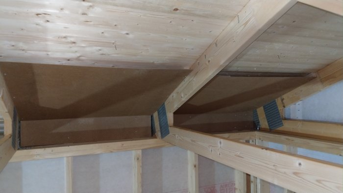 Takstolar i trä med brun MDF-skiva som luftspalt i takkonstruktion.