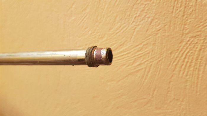VVS-installation med ett kopparrör och en klämring nära änden mot en beige vägg.