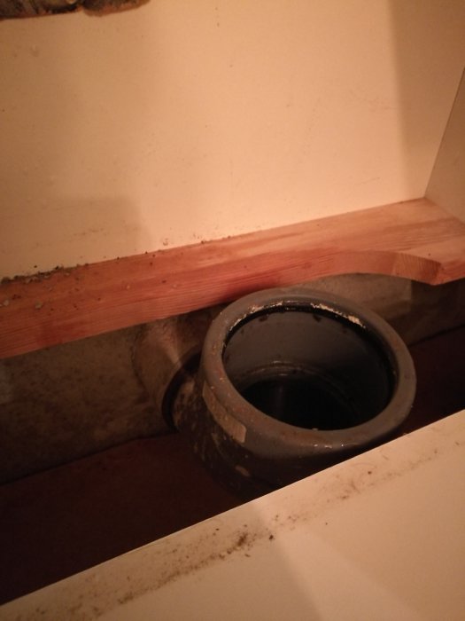 Avloppsrör öppning under köksskåp med synliga smutsavlagringar, fråga om avloppsstopp kan åtgärdas själv.