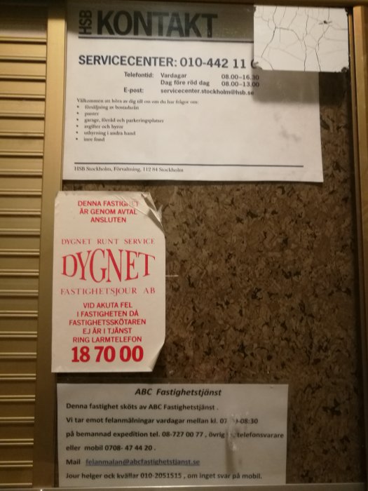 Informationslappar på en vägg med kontaktuppgifter till servicecenter och fastighetsjour för akuta fel.