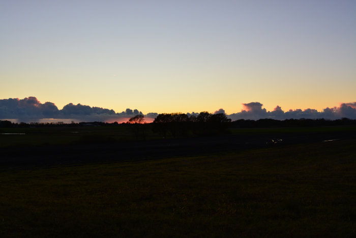 Solnedgång med silhuetter av träd mot en dramatisk himmel den 29 oktober.