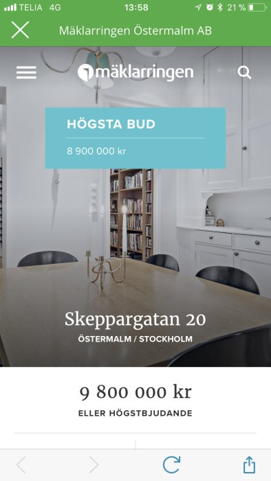 Mobilskärm visar mäklarsida med högsta bud på bostad i Stockholm, inredning i bakgrunden.