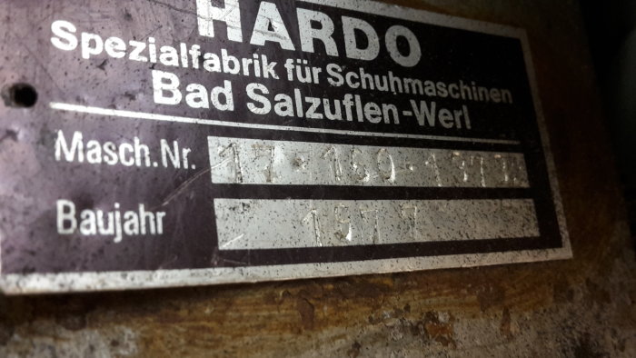Närdeskild bild av ett typskylt på maskineri från HARDO, med texten 'Spezialfabrik für Schuhmaschinen' och produktionsår 1977.
