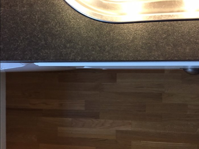 Köksfronter som sticker ut under arbetsytan och ojämn översida av skivan, indikerar sned montering.