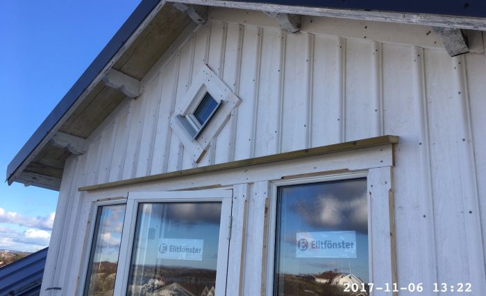 Altandörr och fönster på husfasad med märket Elitfönster, lite skada synlig på träverket.