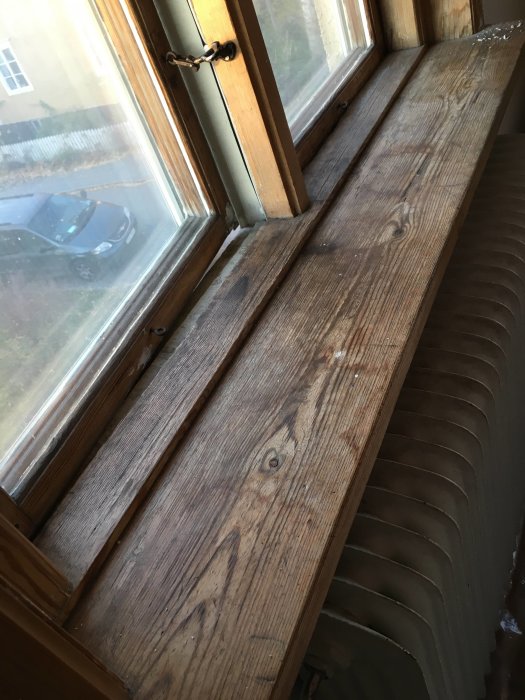 Slipat och grundmålat fönsterbräde med trästruktur framför fönster och radiator.