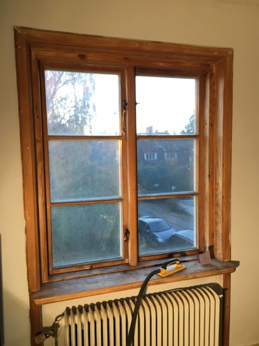 Nyslipat och grundmålat träfönster i rum med utsikt och en element under fönstret.