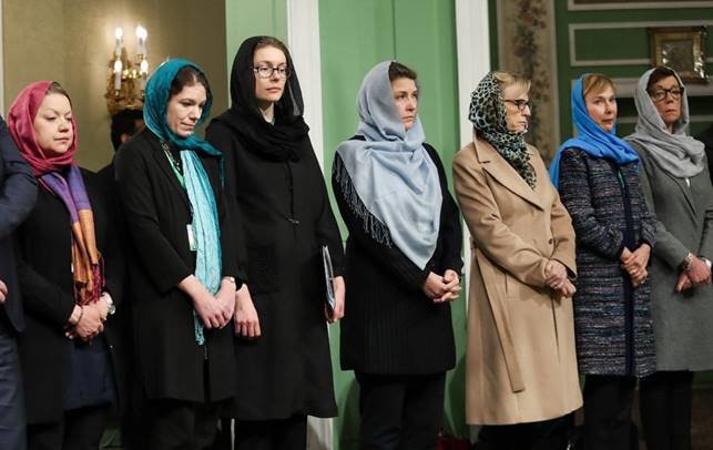 Grupp kvinnor i olika huvuddukar och kläder står uppställda på rad.