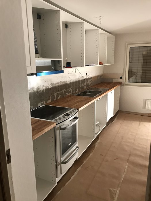 Kök under renovering med nya bänkskivor och en upphöjd spis som är i nivå med skivorna.