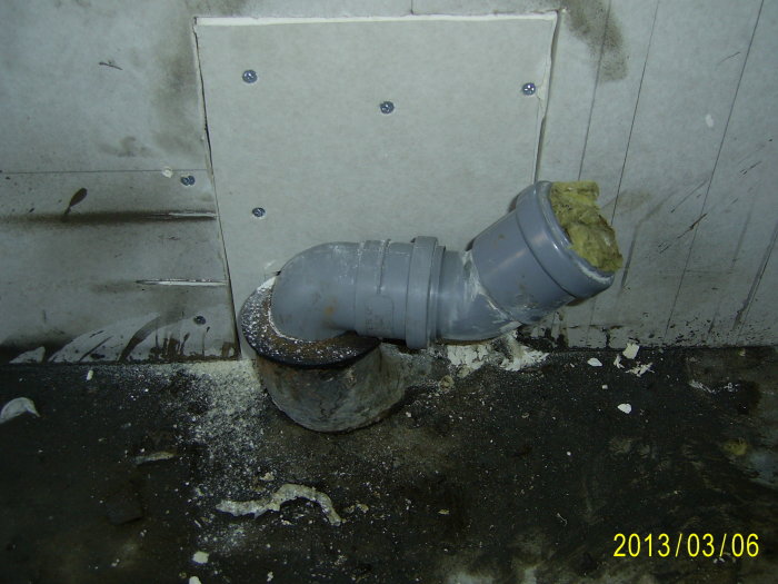 Renoverat avloppsrör med gummistos och grå plastkoppling vid vägg.