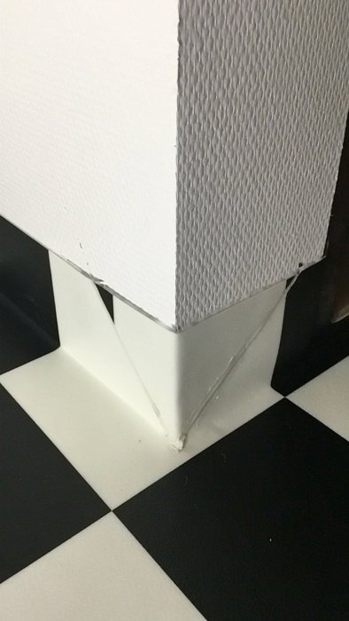 Svartvit rutig vinylgolv med dåligt utförda skarvar och svetsningar vid dörrfoder.